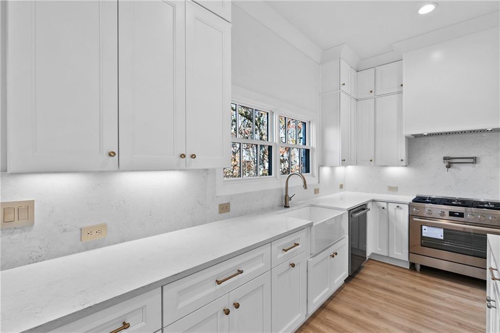 339 Sugarview Road Sugar Hill, GA 30518 - Photo 17 of 53 a kitchen with a sink dishwasher stove and white cabinets with wooden floor