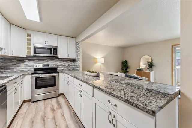a kitchen with granite countertop a sink stove and microwave