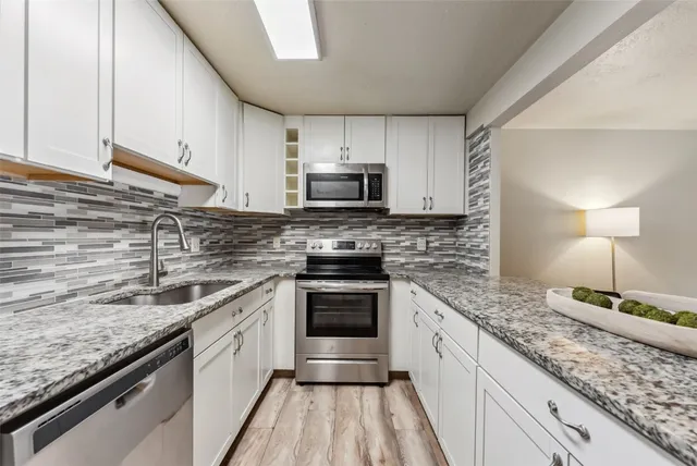 a kitchen with stainless steel appliances granite countertop a sink stove and microwave
