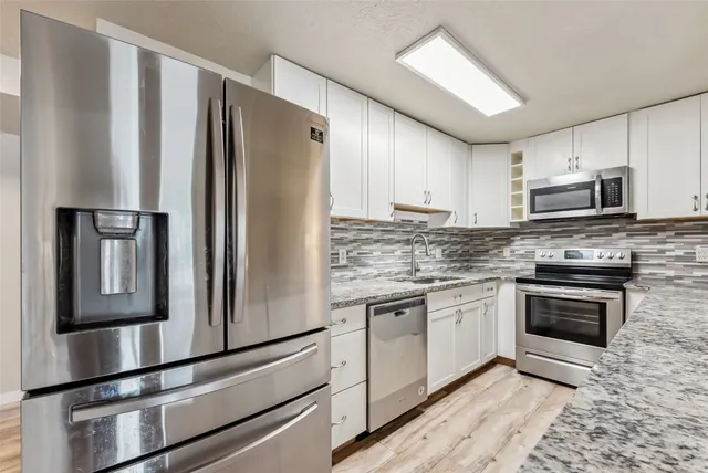 a kitchen with granite countertop a refrigerator stove and microwave