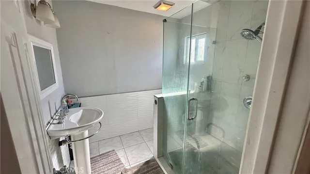 a bathroom with a sink a toilet a mirror and shower