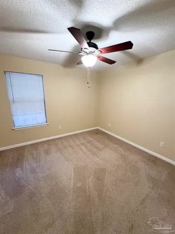 an empty room with a ceiling fan and window