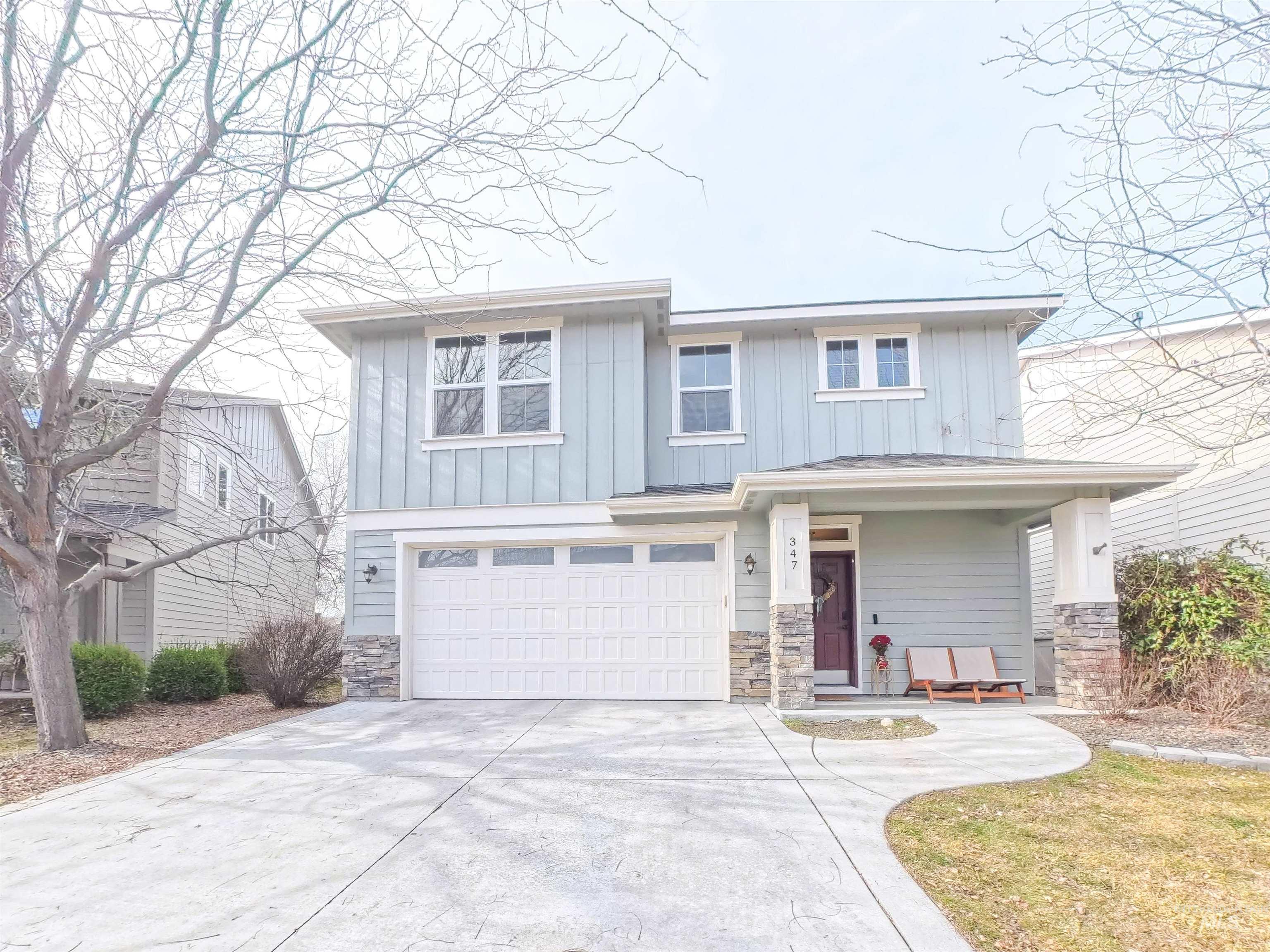 Craftsman house featuring stone siding, an attached garage, concrete driveway, and board and batten siding