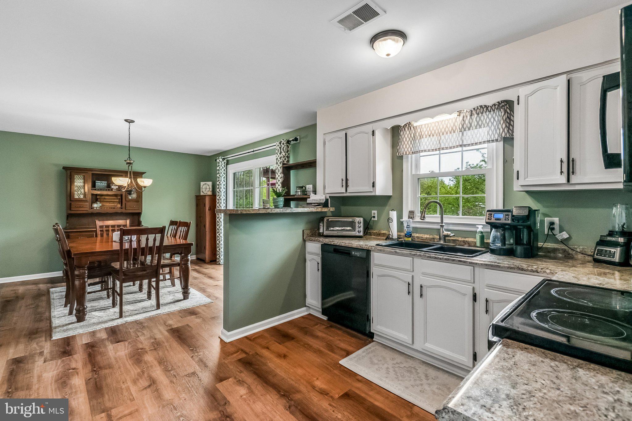 6774 Grays Mill Road Warrenton, VA 20187 - Photo 18 of 35 a kitchen with granite countertop a stove a sink a dining table and chairs with wooden floor