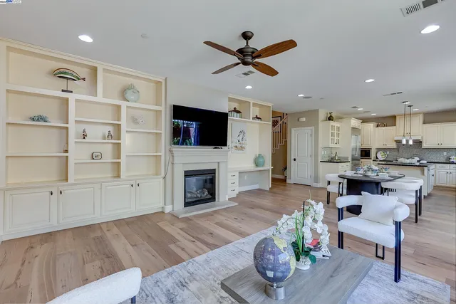 a kitchen with a dining table chairs cabinets wooden floor and appliances