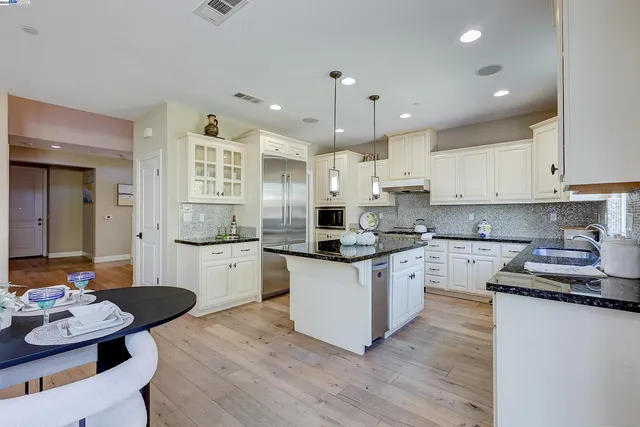 a kitchen with stainless steel appliances granite countertop a stove a white cabinets and a granite counter tops