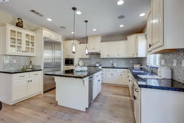 a kitchen with stainless steel appliances granite countertop a sink a stove a dining table and chairs