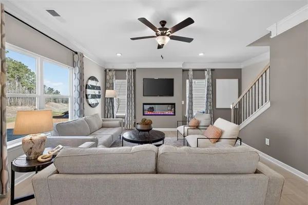 a living room with furniture flat screen tv and a large window