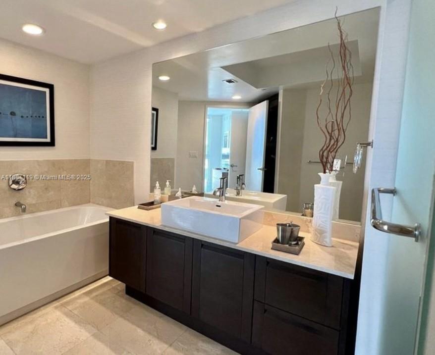 250 Sunny Isles Boulevard, Unit 31603 Sunny Isles Beach, FL 33160 - Photo 4 of 20 a bathroom with a tub sink and mirror