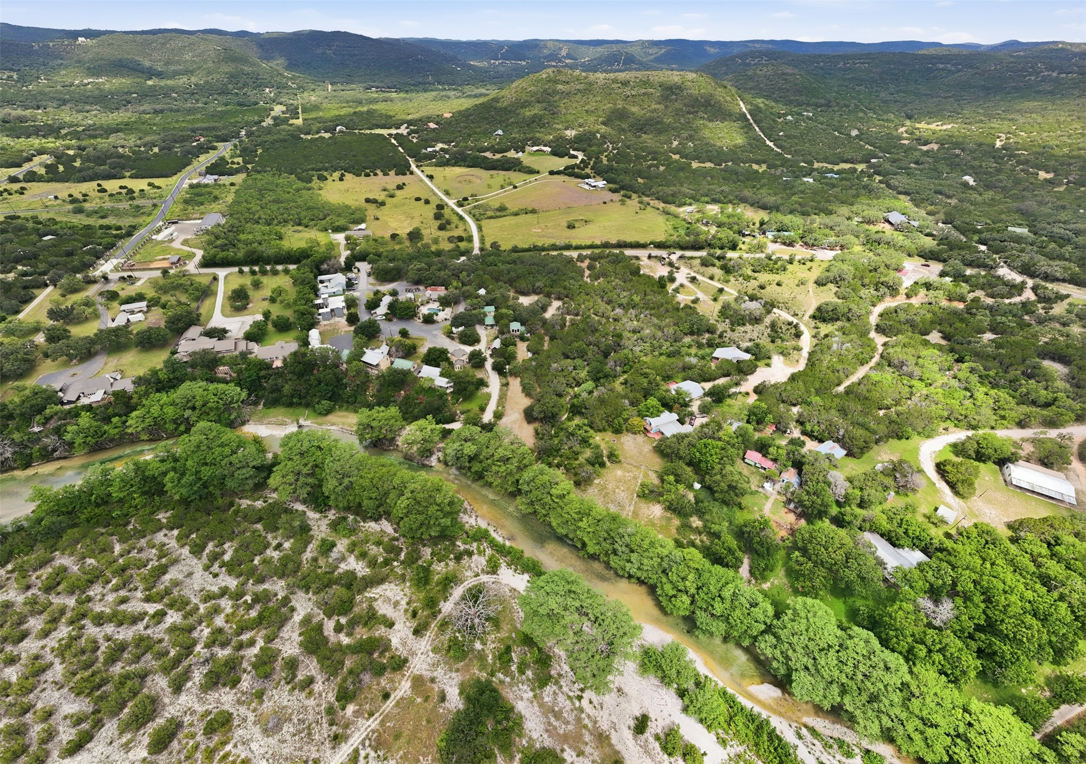 1260 Magers Road Concan, TX 78838 - Photo 37 of 40 Aerial view captures a serene river winding through a vibrant green landscape with scattered homes.