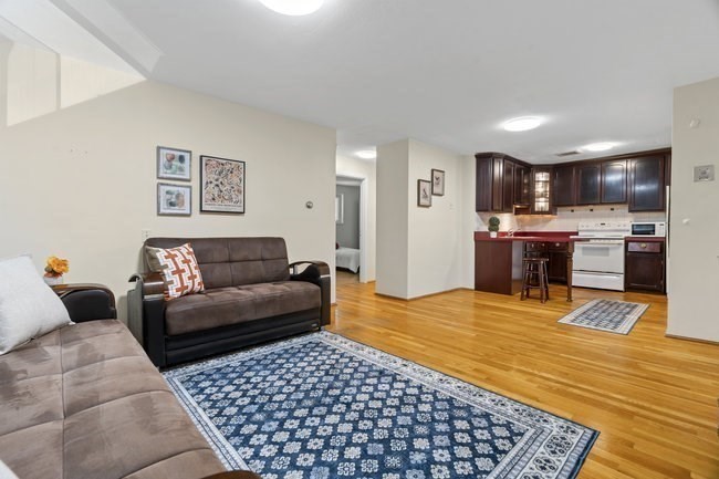 357 Faneuil Street, Unit 12 Boston, MA 02135 - Photo 11 of 15 a living room with stainless steel appliances kitchen island granite countertop a couch and wooden floor