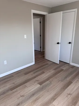 a view of an empty room with wooden floor and closet area