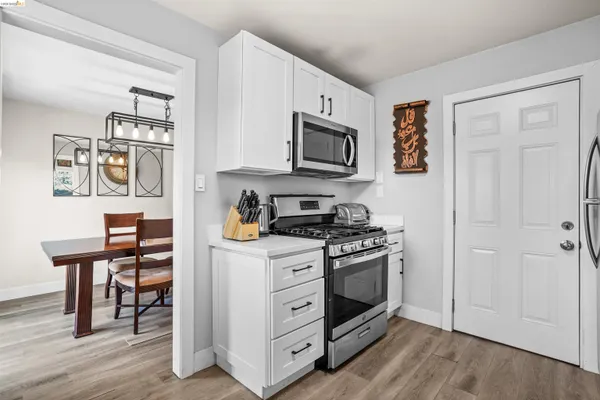 a kitchen with stainless steel appliances white cabinets and wooden floor