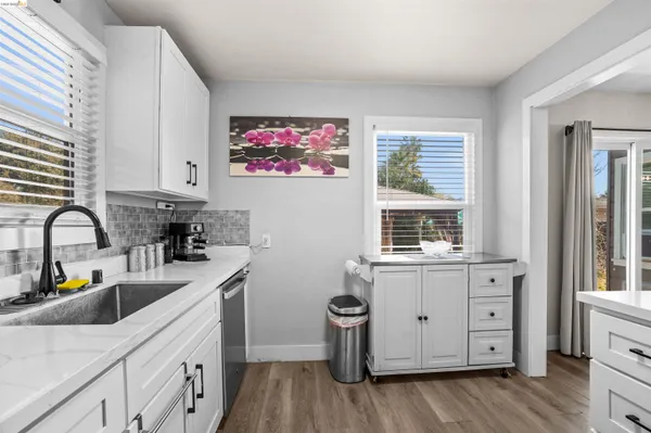 a kitchen with granite countertop white cabinets and wooden floor