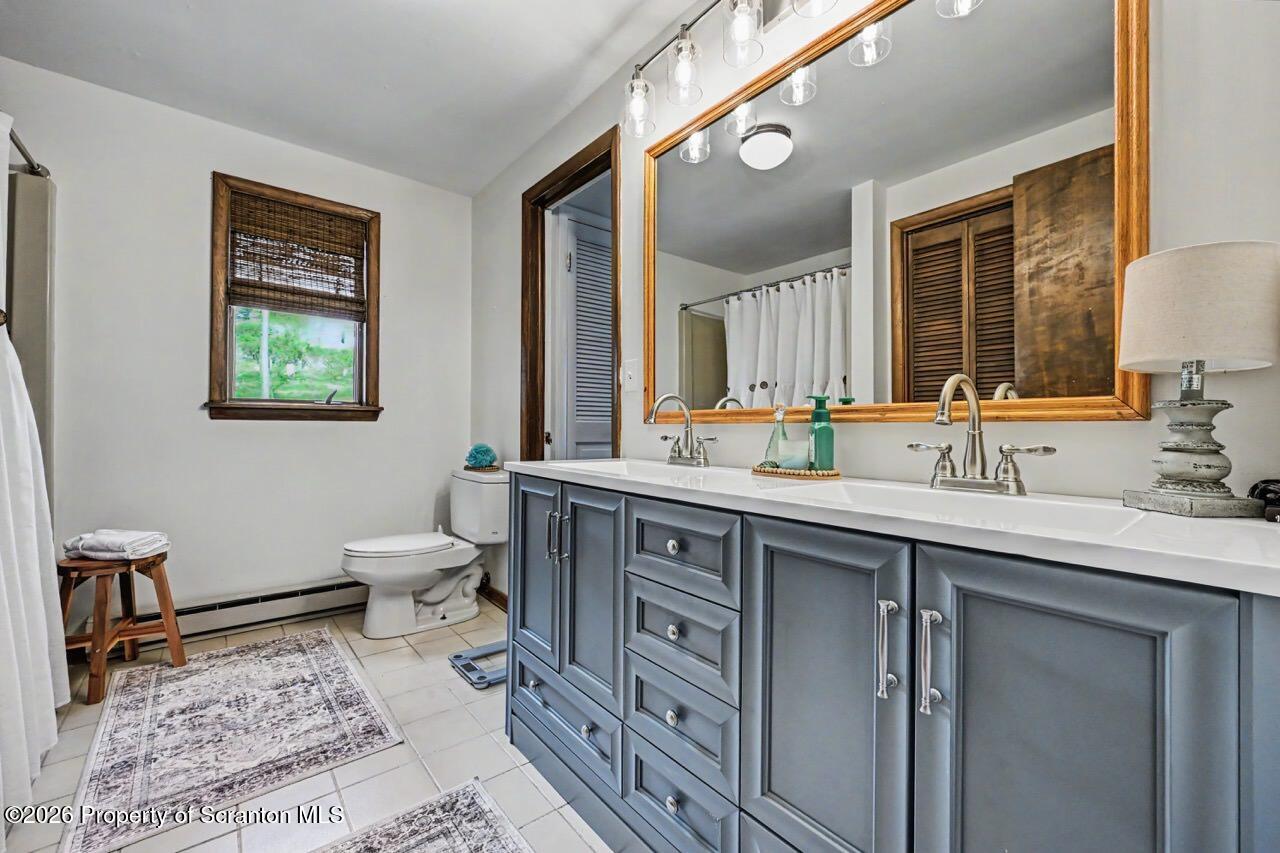 719 Scott Road Clarks Summit, PA 18411 - Photo 34 of 51 a spacious bathroom with a double vanity sink a mirror and a toilet