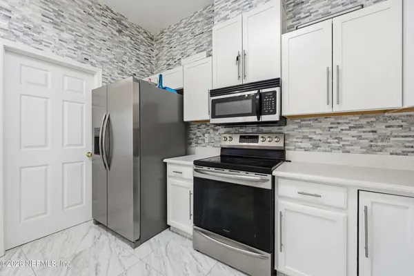 a kitchen with stainless steel appliances white cabinets and a stove top oven