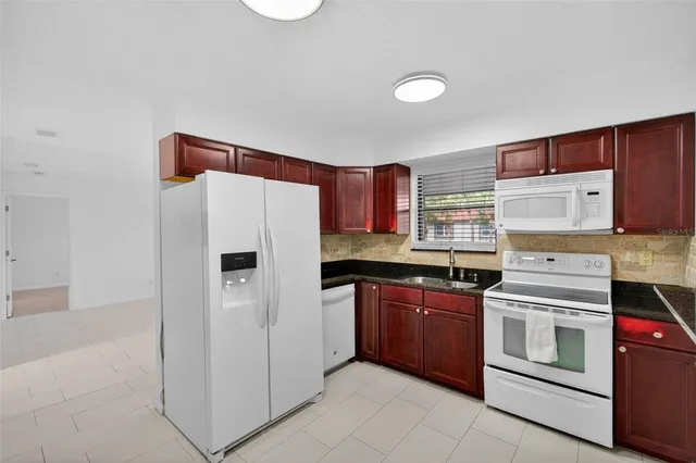 a kitchen with granite countertop a refrigerator sink and cabinets