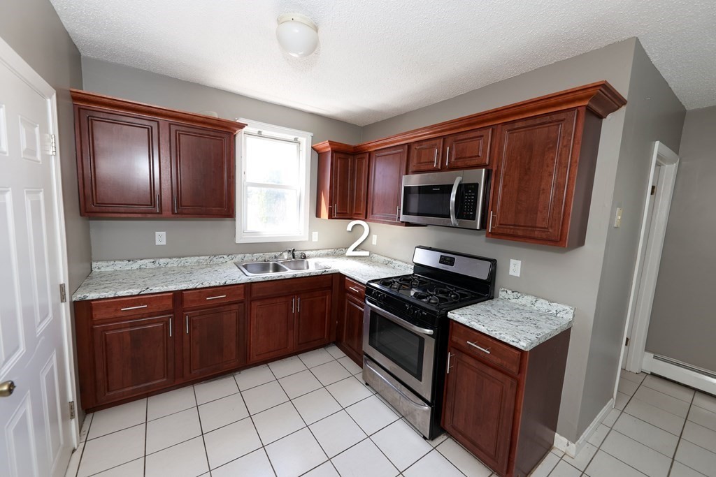 459 Snell Street Fall River, MA 02721 - Photo 1 of 42 a kitchen with granite countertop wooden cabinets stainless steel appliances and a window