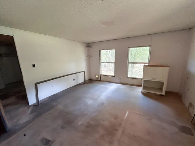 an empty room with windows and fireplace