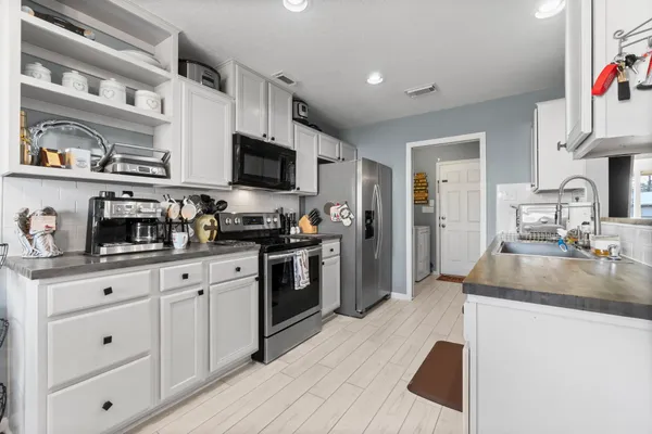a kitchen with granite countertop a sink stainless steel appliances and white cabinets