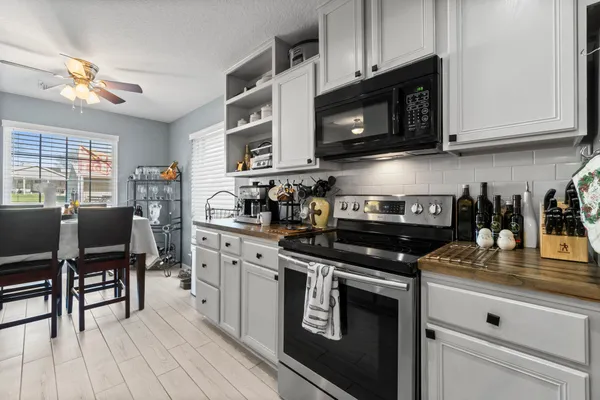 a kitchen with stainless steel appliances granite countertop a stove top oven a sink dishwasher a dining table and chairs with wooden floor