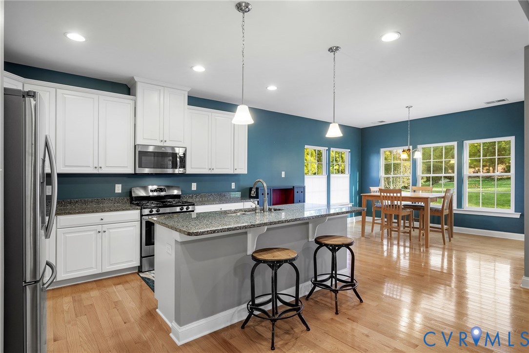 3437 Kendal Crossing Terrace Midlothian, VA 23113 - Photo 11 of 31 a kitchen with stainless steel appliances granite countertop a stove a refrigerator a kitchen island a dining table and chairs with wooden floor