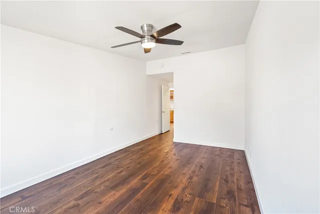 an empty room with wooden floor and a ceiling fan