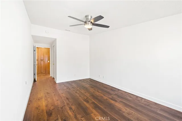 a view of a room with wooden floor and a ceiling fan