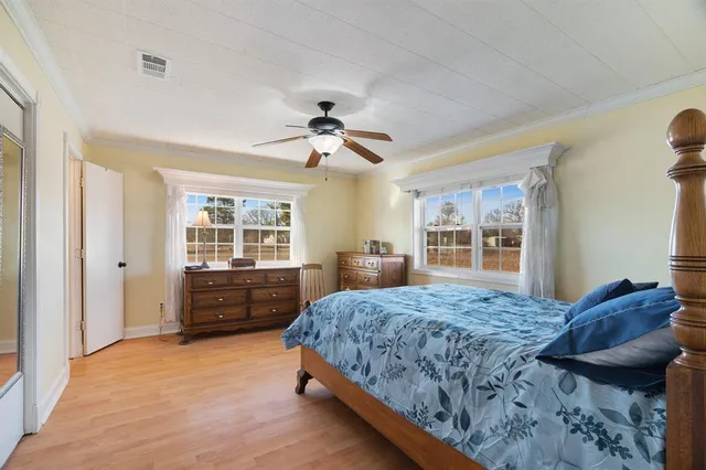 a bedroom with a bed and dresser with wooden floor