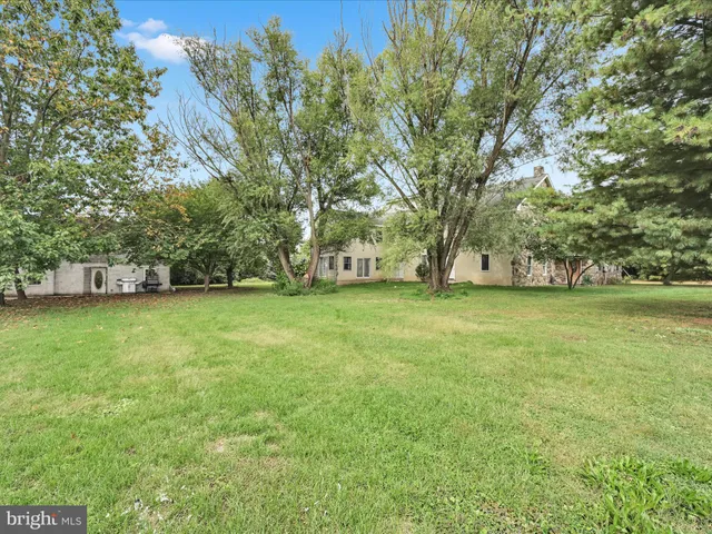 a view of a white house with a big yard and large tree