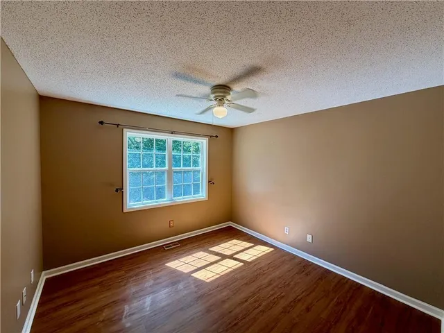 an empty room with wooden floor and fan
