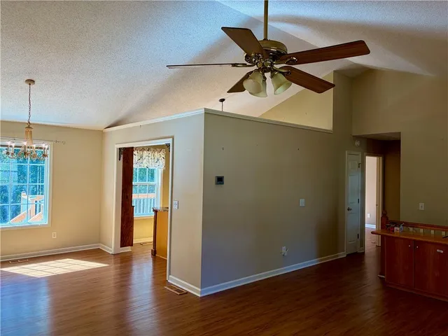 a view of an empty room with wooden floor and a ceiling fan
