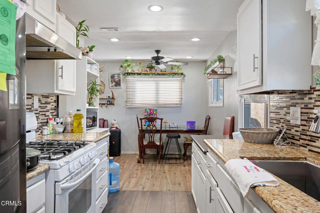 145 Homer Street Oxnard, CA 93033 - Photo 8 of 15 a kitchen with stainless steel appliances a stove a sink dishwasher and a dining table with wooden floor