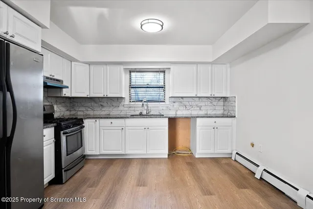 a kitchen with granite countertop a sink cabinets stainless steel appliances and a window