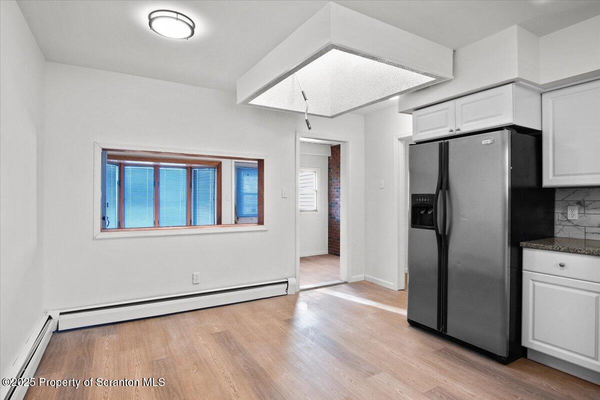 134 Lampman Street Avoca, PA 18641 - Photo 5 of 34 a view of a refrigerator in kitchen and an empty room with wooden floor