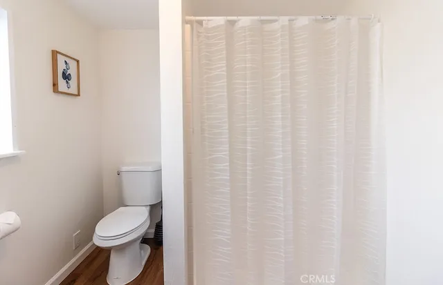 a white toilet sitting next to a white curtain
