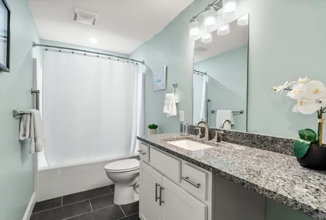 a bathroom with a granite countertop sink toilet a large mirror a bathtub and shower