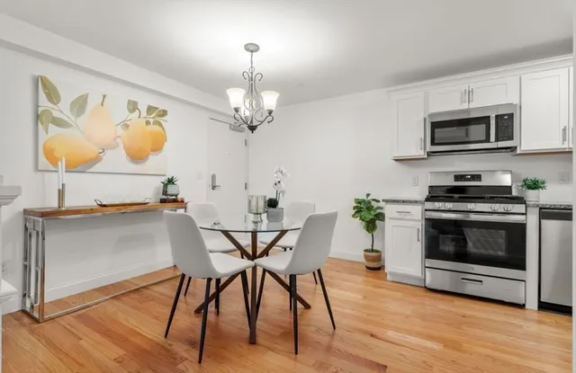 a view of a dining room with furniture wooden floor kitchen and a chandelier