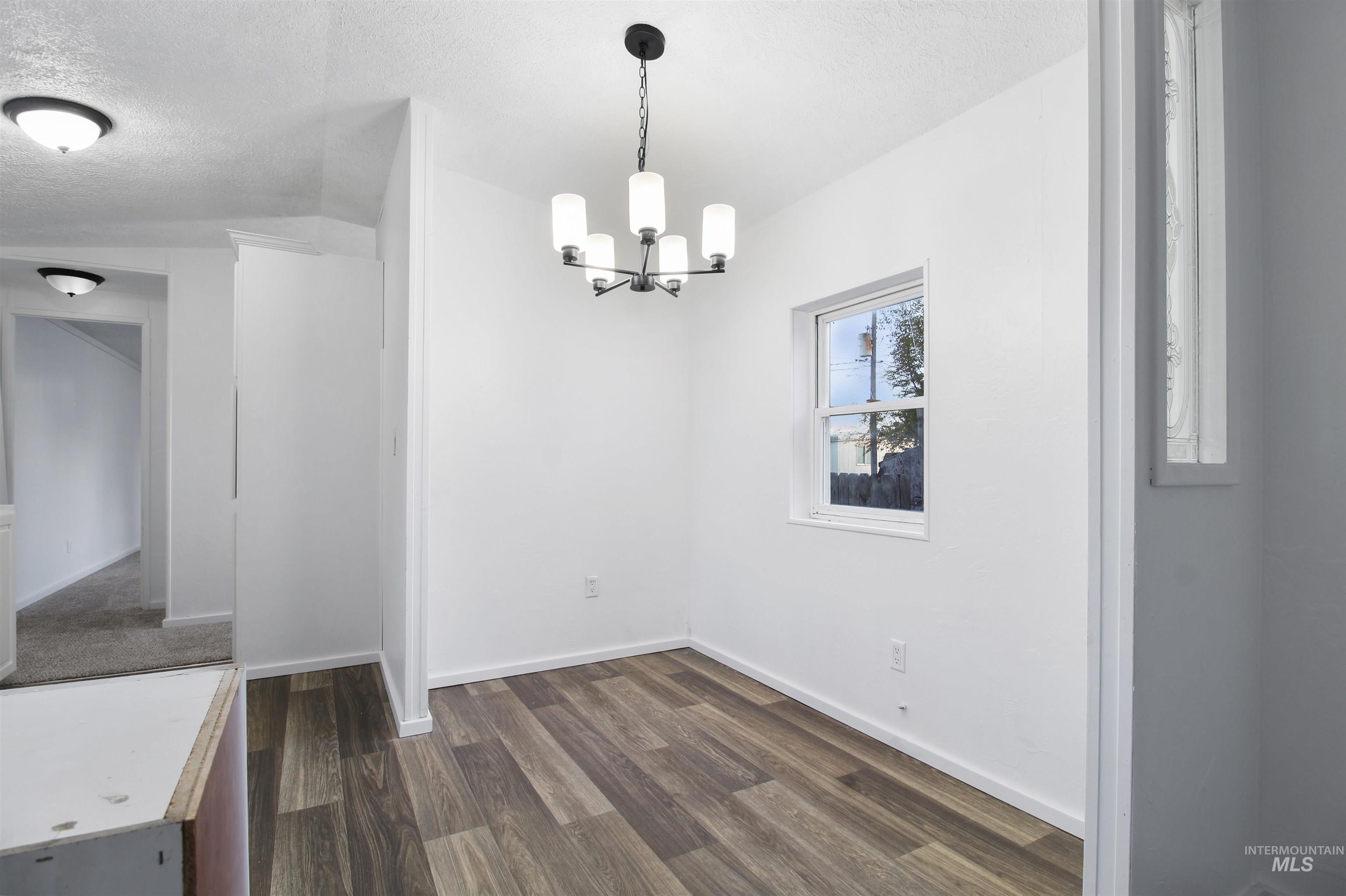 377 South 200 West, Unit 36 Rupert, ID 83350 - Photo 13 of 31 Unfurnished dining area featuring dark wood-style floors, a textured ceiling, and a chandelier