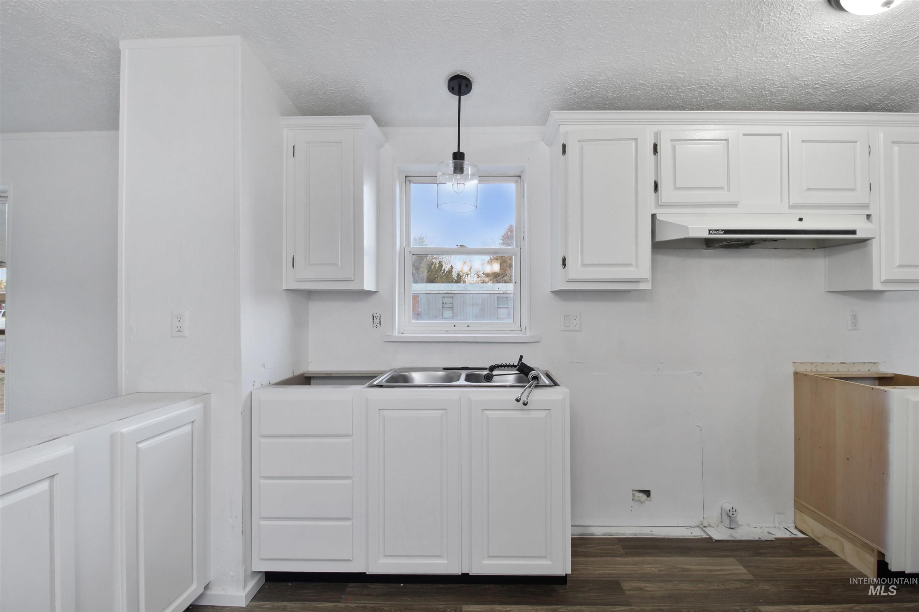 377 South 200 West, Unit 36 Rupert, ID 83350 - Photo 15 of 31 Kitchen with white cabinets, a textured ceiling, dark wood-style floors, pendant lighting, and light countertops