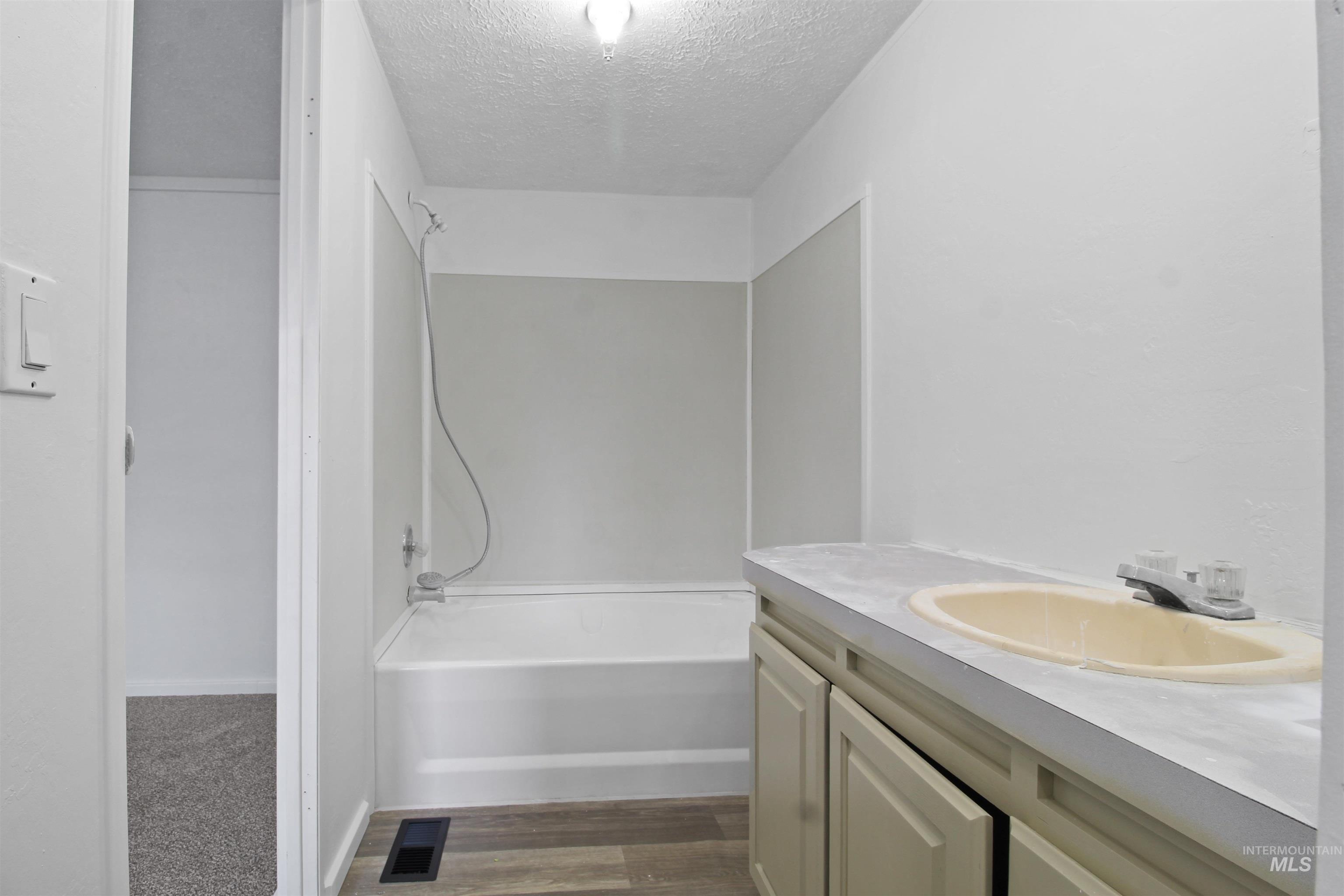377 South 200 West, Unit 36 Rupert, ID 83350 - Photo 18 of 27 Full bath with a textured ceiling, vanity, shower / bath combination, and dark wood finished floors
