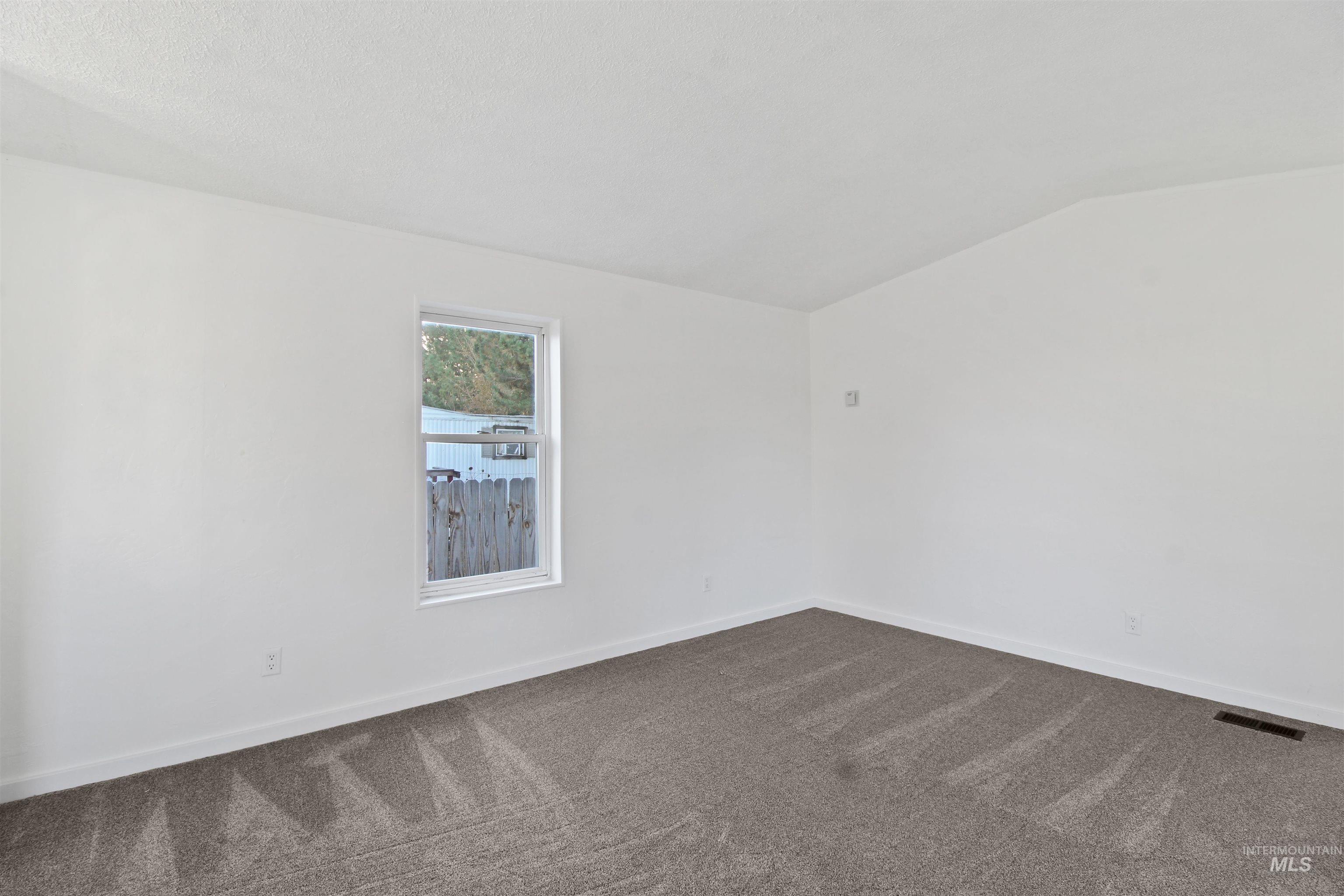 377 South 200 West, Unit 36 Rupert, ID 83350 - Photo 25 of 31 Empty room with dark carpet and vaulted ceiling