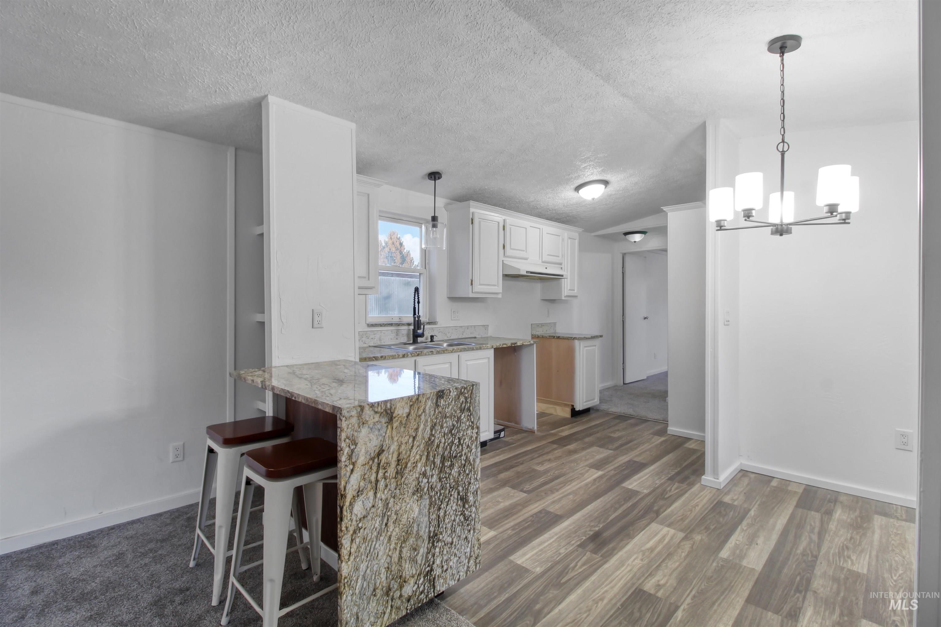 377 South 200 West, Unit 36 Rupert, ID 83350 - Photo 3 of 31 Kitchen with a kitchen bar, white cabinets, a peninsula, a chandelier, and light stone counters