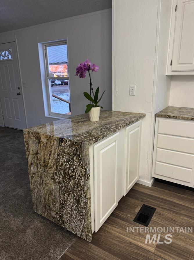 377 South 200 West, Unit 36 Rupert, ID 83350 - Photo 9 of 31 Kitchen with dark stone countertops, white cabinets, a peninsula, dark wood-style flooring, and a textured ceiling