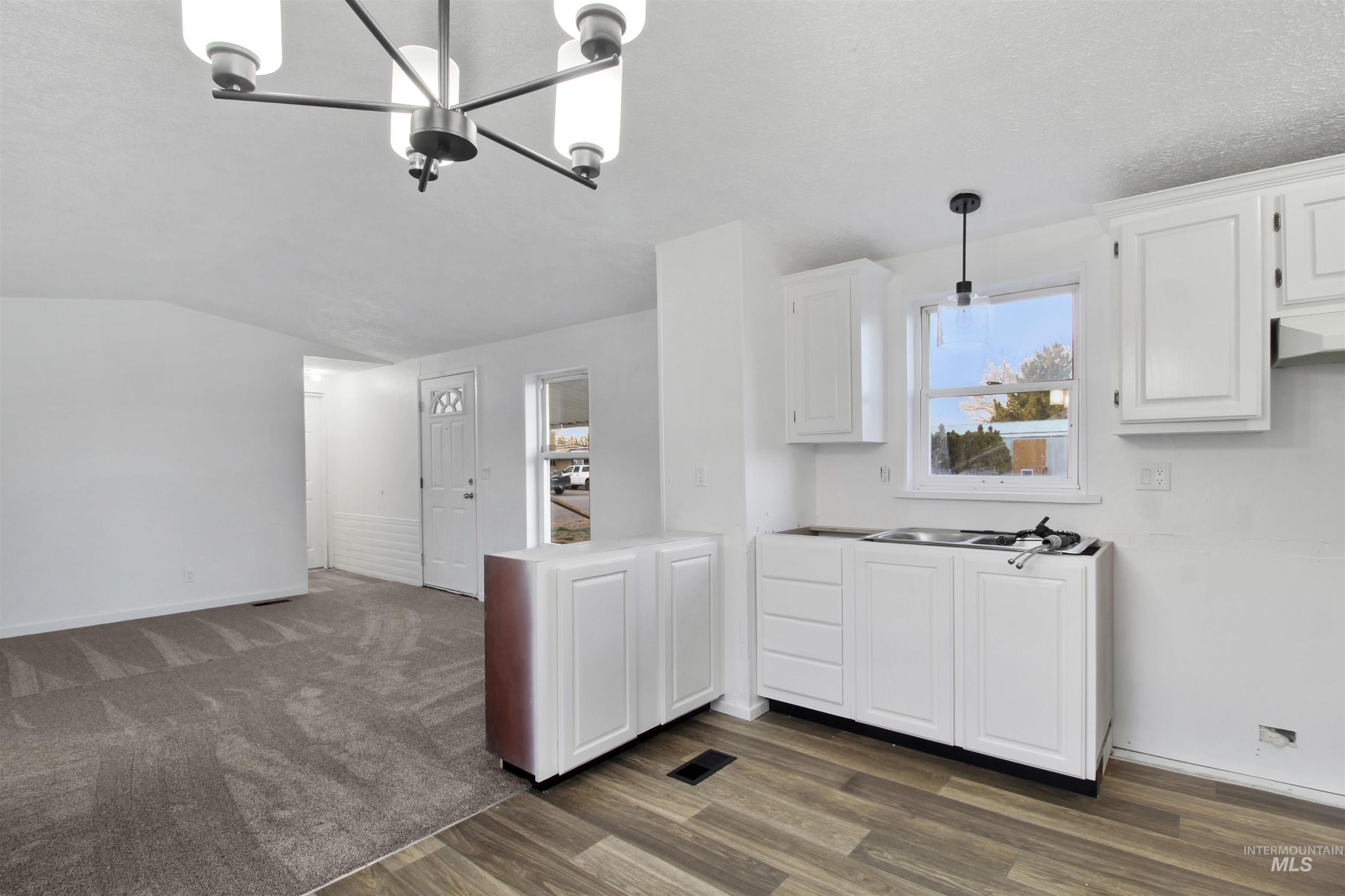 377 South 200 West, Unit 36 Rupert, ID 83350 - Photo 10 of 27 Kitchen featuring hanging light fixtures, white cabinets, dark wood-type flooring, light countertops, and a chandelier