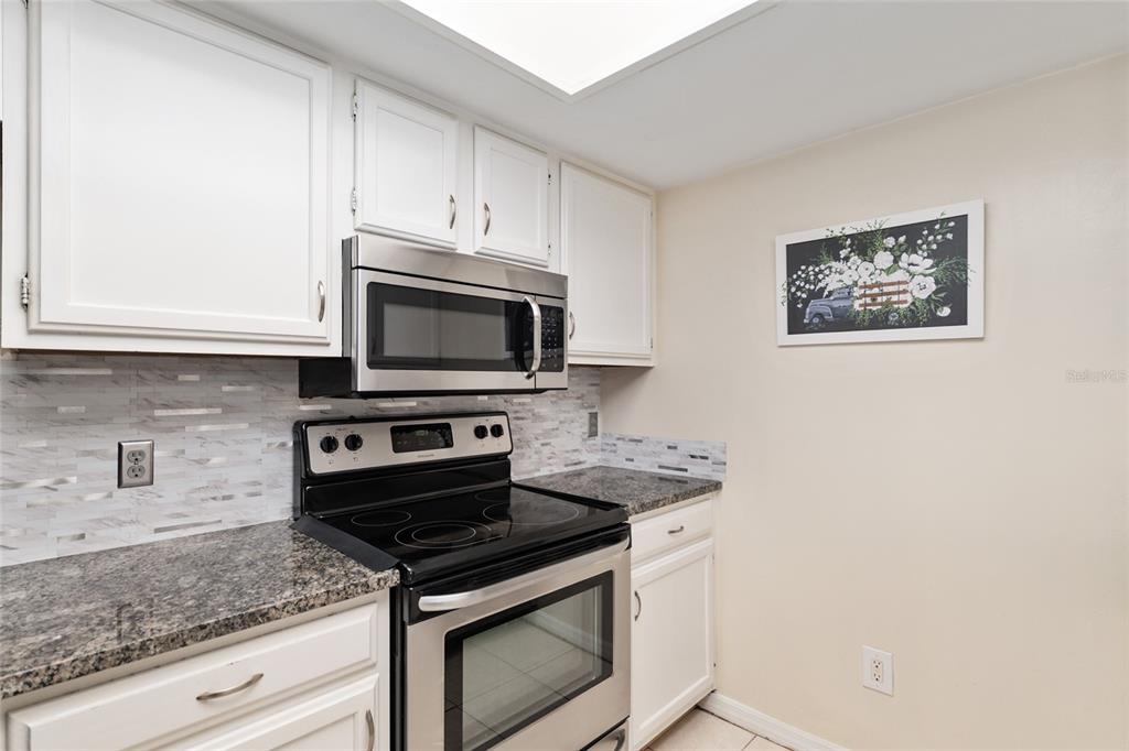 7200 Southwest 8th Avenue, Unit E29 Gainesville, FL 32607 - Photo 23 of 47 a kitchen with granite countertop white cabinets stainless steel appliances and a counter space