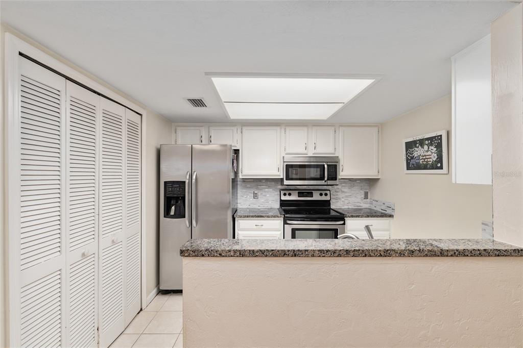 7200 Southwest 8th Avenue, Unit E29 Gainesville, FL 32607 - Photo 25 of 47 a kitchen with stainless steel appliances granite countertop a refrigerator a stove a sink and a microwave