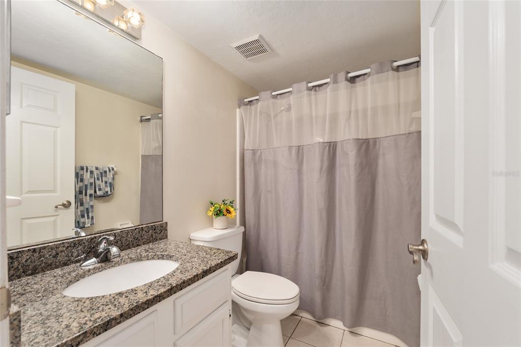 7200 Southwest 8th Avenue, Unit E29 Gainesville, FL 32607 - Photo 29 of 47 a bathroom with a granite countertop sink toilet and a mirror
