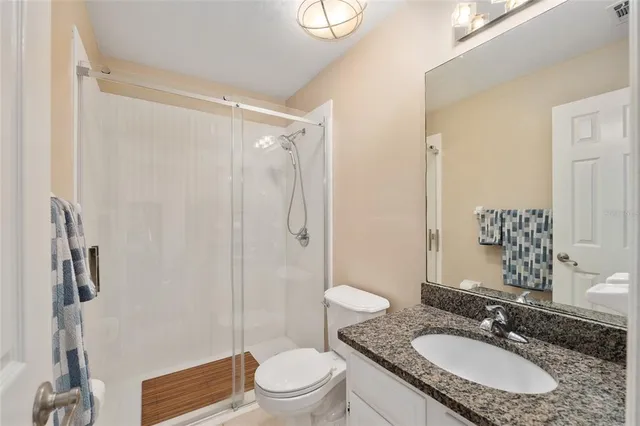 a bathroom with a granite countertop sink toilet a mirror a vanity and shower