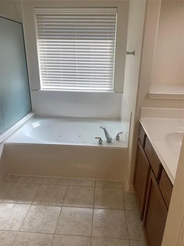 a bathroom with a tub sink and mirror